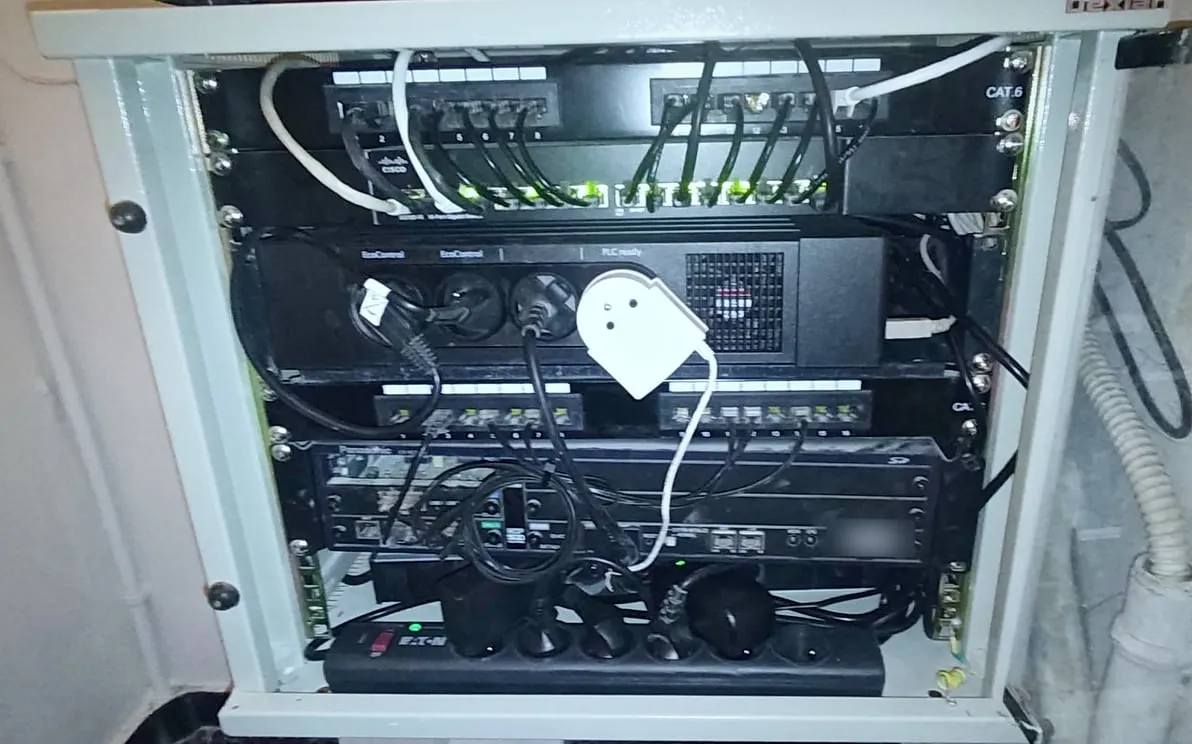 La même baie ouverte et rangée : panneaux de brassage, switch Cisco, câbles courts alignés, bloc de prises et standard téléphonique en dessous