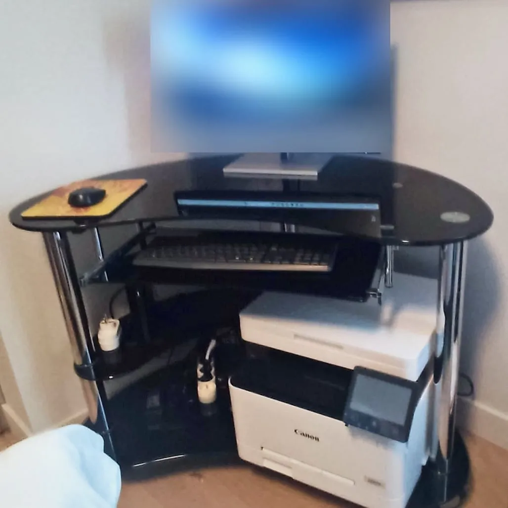Nouvel écran, image floutée, posé sur le même bureau d’angle, clavier sur la tablette et imprimante multifonction Canon en dessous