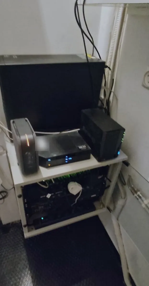 Le même recoin rangé : box, routeur et NAS Synology alignés sur la baie, switch allumé dans la baie, sol dégagé