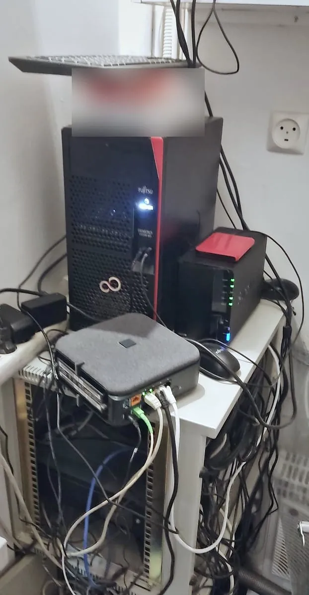 Serveur tour Fujitsu et NAS Synology posés sur une baie basse, câbles emmêlés en dessous