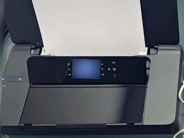 Imprimante mobile noire, capot ouvert, une feuille blanche engagée