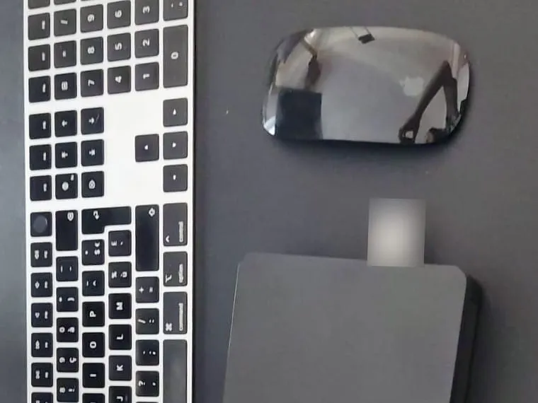 Clavier et souris sans fil et petit boîtier noir posés sur un bureau noir