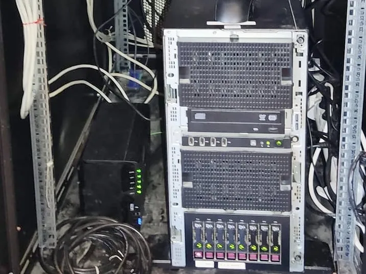 Serveur tour HP ProLiant installé au bas d’une baie réseau, entre les montants et les câbles